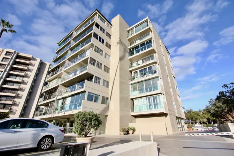 A SUNNY DAY IN THE VISTA DEL LIDO WITH THE APARTMENT, CAR PARKING, FLOWER POT, TREES