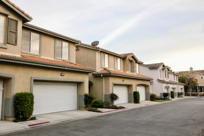 A wide angle view of 4 residential buildings. the first two painted brown, and the third white