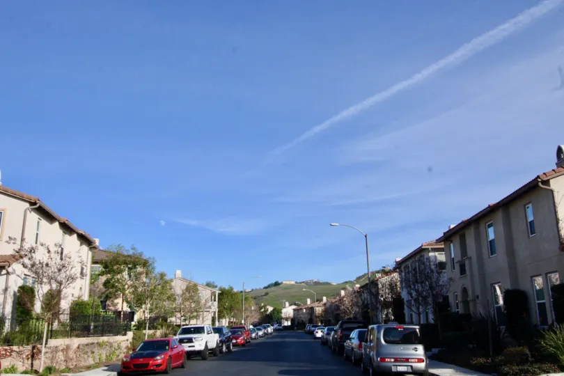 A sunny day with cars parked on either side of the road in the Casita community