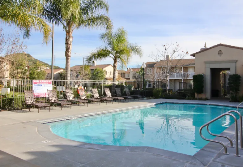 A beautiful building and swimming pool in Casita with beautiful shrubs and beautiful trees near the resting chairs.