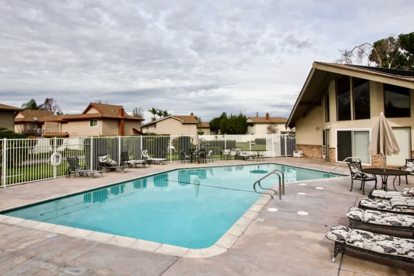 The pool in the Golden Circle community on a cloudy day with deck furniture