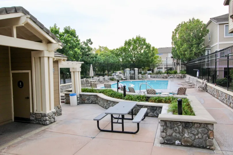 Inside the apartment in Huntington has swimming pool with seating chairs and tables with trees and closing umbrella
