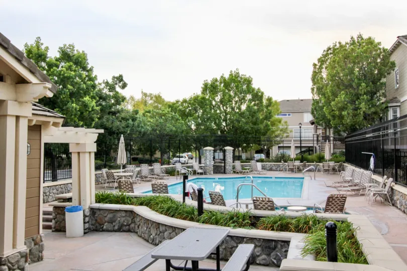 A serene pool in the backyard of a house with a white gate