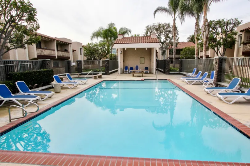 A pool in La Veta Monterey with deck chairs and a gate on a sunny day.
