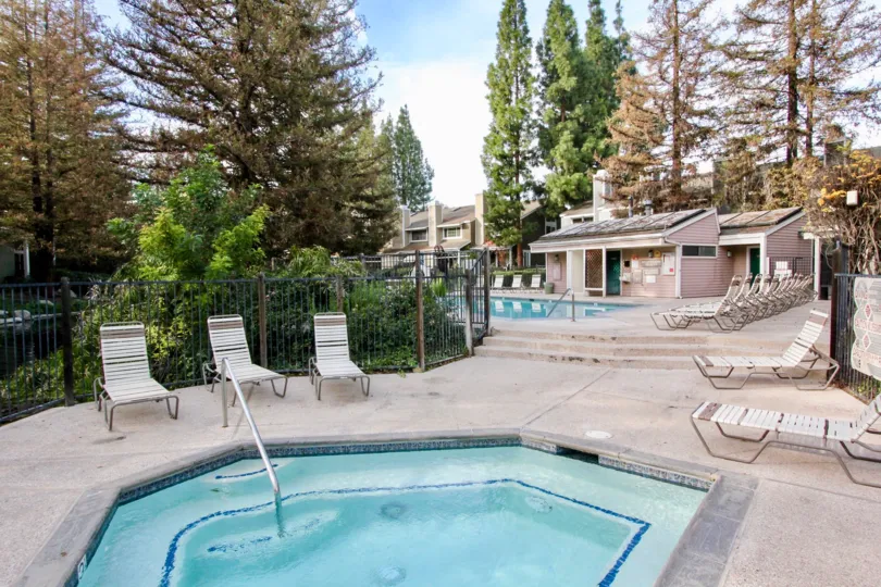 A pool in the Morningside on the Lake with deck chairs and a fence.