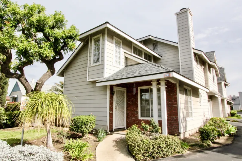 A grey and red brick house in Orange Creek with trees and bushes on a sunny day