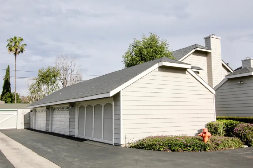 A light grey color house and garage with bushes around them in the orange creek community in orange, california.