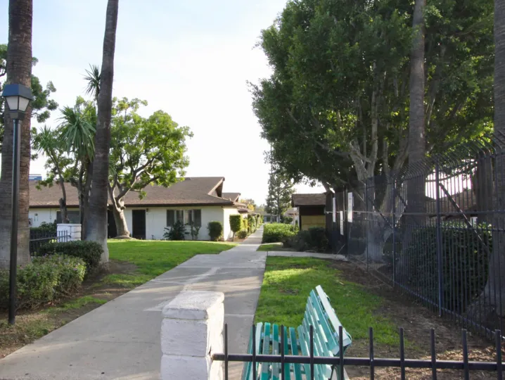 A sidewalk in the Park 72 community with trees and fences