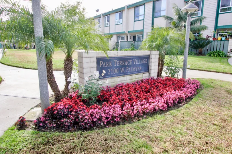 A sunny day at the Park Terrace Village, with its sign surrounded by beautiful flowers