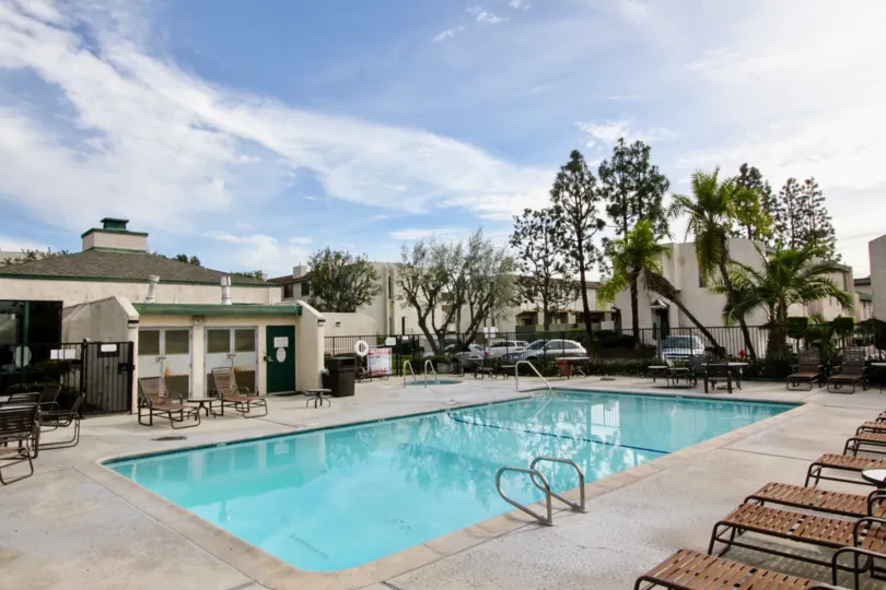 The pool in Park Terrace Village with lawn chairs and tables on the sunny day.