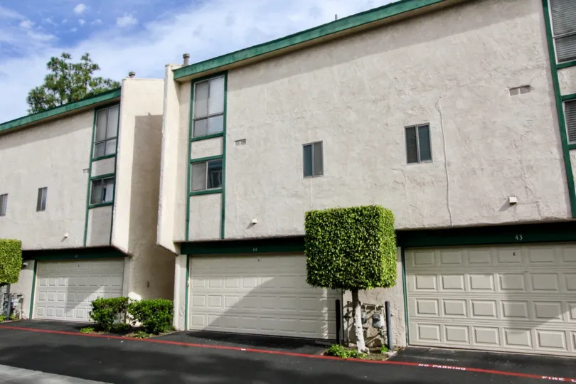 White apartment buildings in Park Terrace Village with bushes and trees.