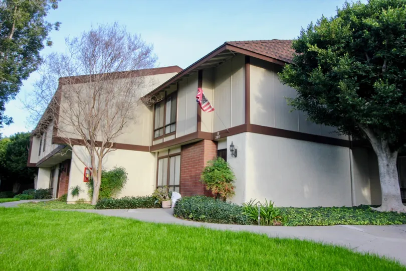 A sunny day in the Smoketree Orange Townhomes community with a sidewalk and a flag
