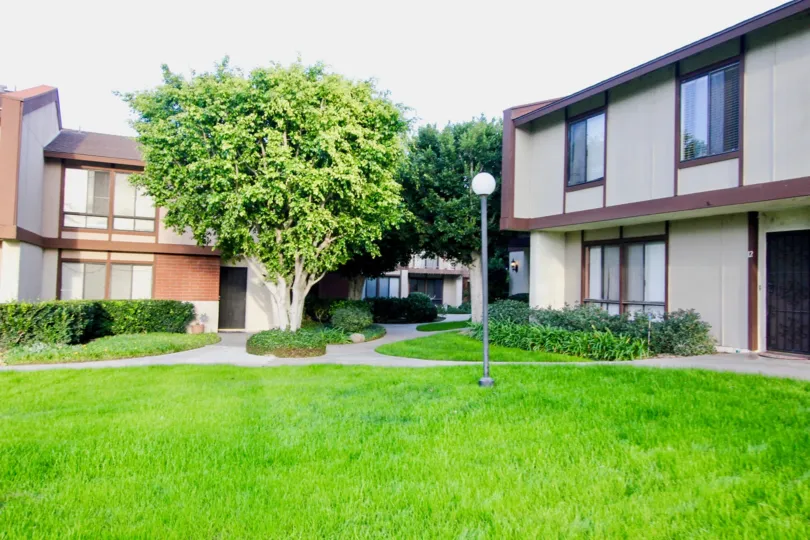 The green lawn in front of Smoketree Orange Townhomes with bushes and trees