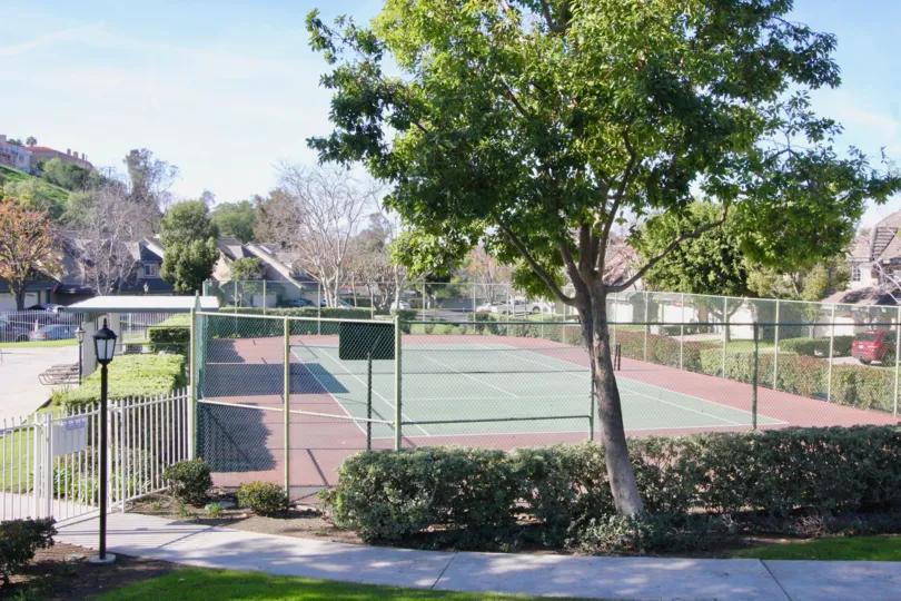 A lawn tennis court with an all round fence inside the Stonehenge community in orange city