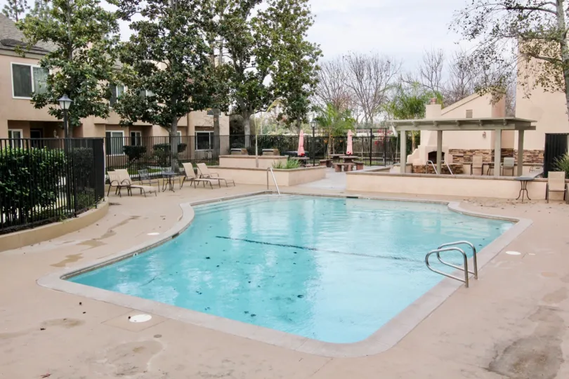 A pool and chairs and trees in the Tamarin Orange community.