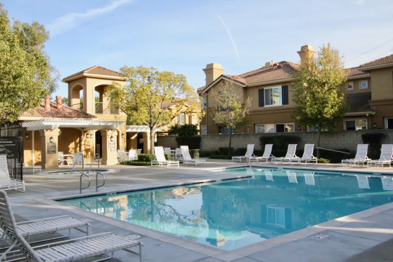 A sunny day in the The Bluffs at Belmont with a swimming pool and chairs.
