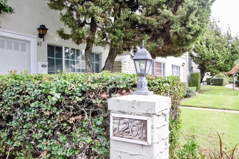 A beautiful wight color building in the The Californian with some shrubs, lawn and trees.