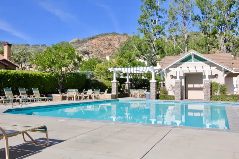 A pool in the Canyon Hills community with deck chairs and tables.