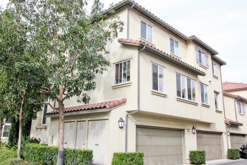 A beautiful white and grey house in the Timber Hill with beautiful ornamental plants and big trees near the road side.