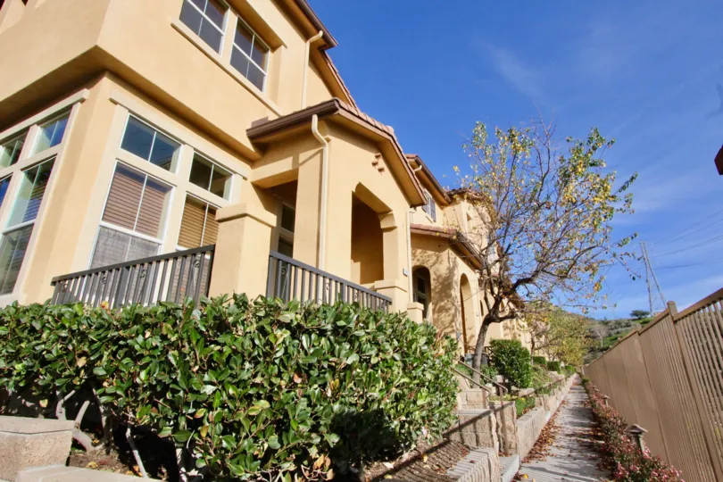 Sun lit, fence-lined walkway in front of a row our houses in the Tremont community