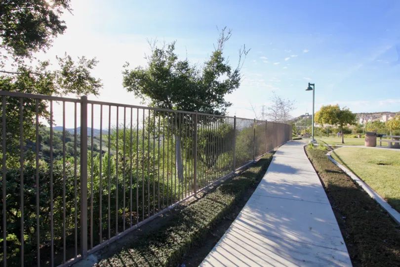 a sidewalk winds near a fence at the Tremont Condos/