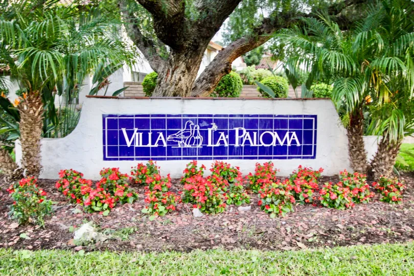 The sign outside the Villa La Paloma with flowers and palm trees