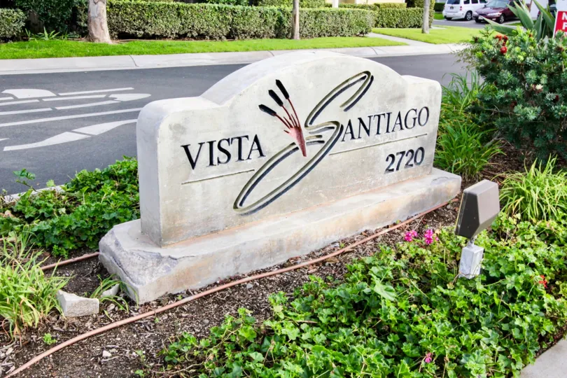 A sign by the street in Vista Santiago with flowers and bushes