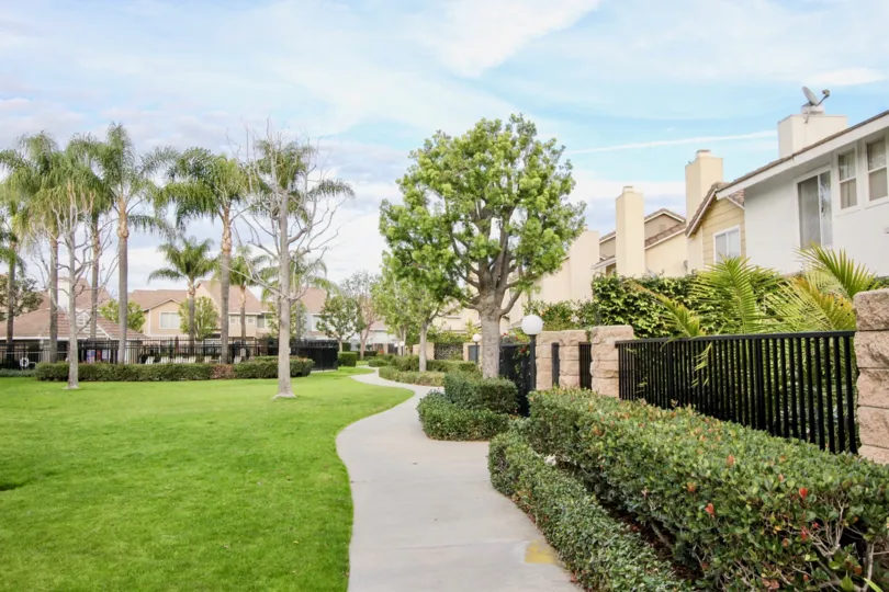 A slender paved walkway lined with shrubs at Vista Santiago in Orange CA