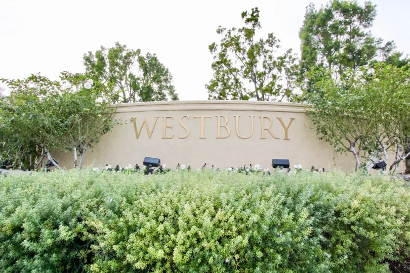 Large golden community sign on a wall in front of Westgate in Orange CA