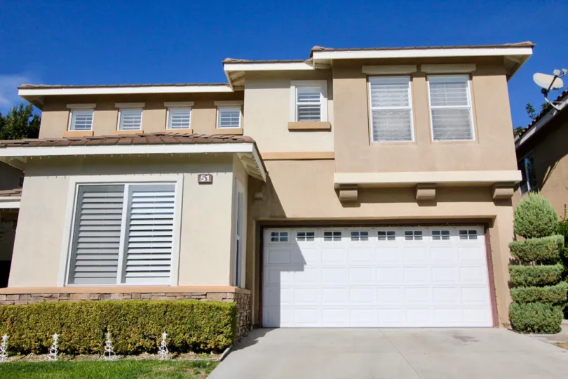 A spiraled tall hedge sits next to a garage in the Ballantree community