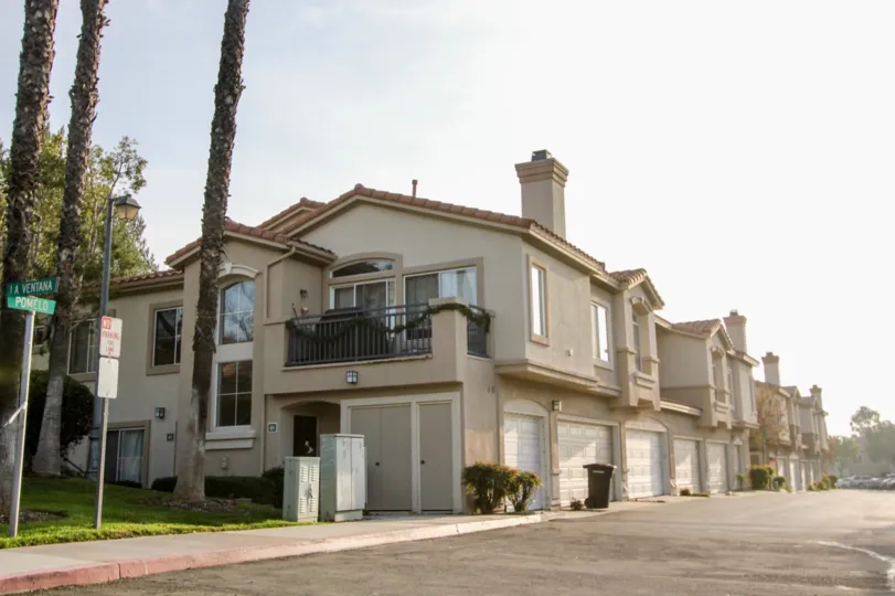 A sunny day by some Bella Ventana houses which all have multiple garages and windows visible, along with trees next to some