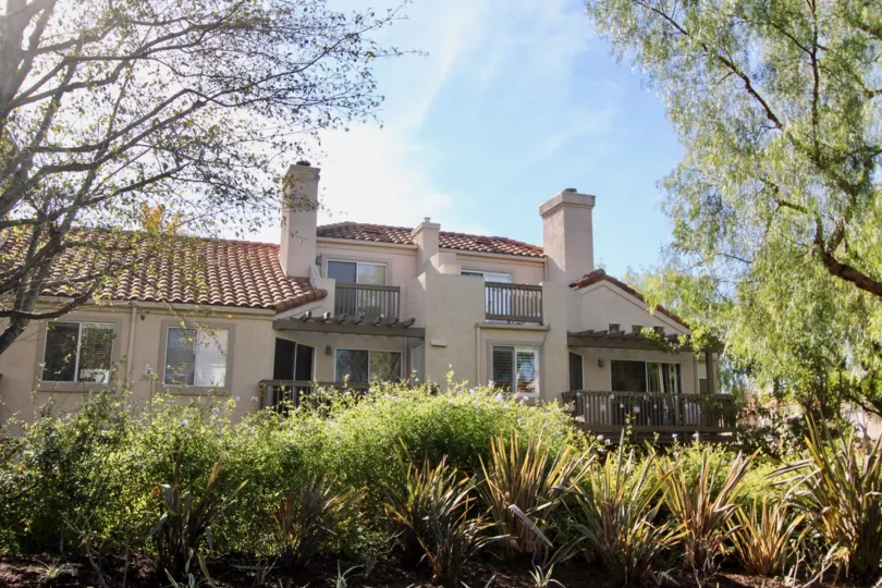 A large house on a sunny day with trees and bushes in the landscaping in the Brisa del Lago Community