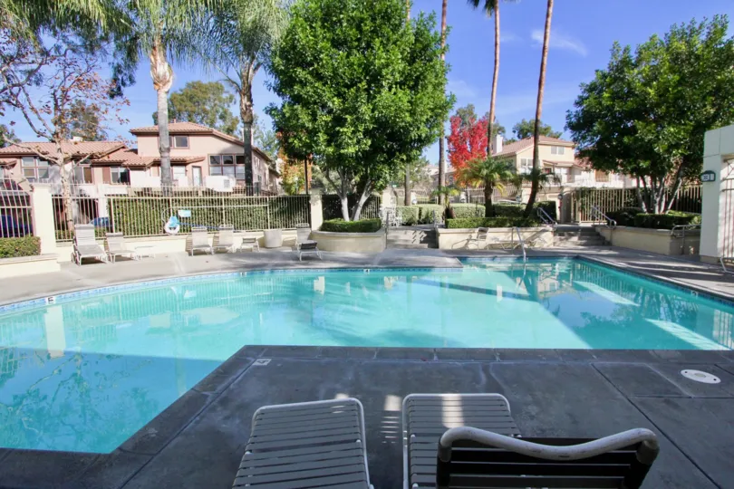 A public pool with concrete paving and white fences in the Cabo Vista community.