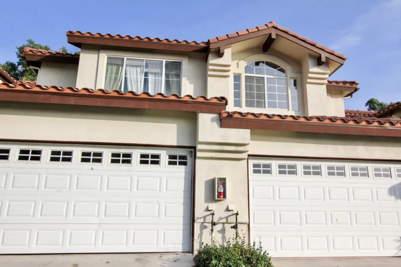 A tan home with red roof and two garages in Candelero community in Rancho Santa Margarita, California.