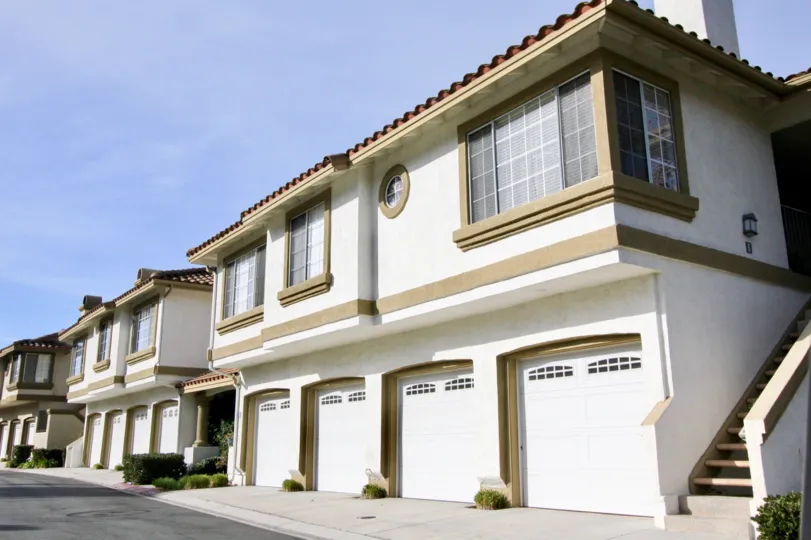 A street view of the private two garage parking at Casafina with light colored buildings and dark roof and trim