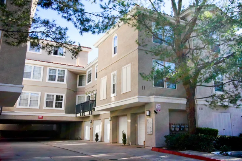 Street level view of the three story Cierra Del Lago community with ground level private garage parking and tall trees