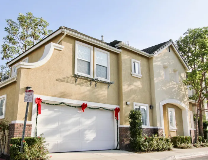 A sunny day at a house in the Magnolia area with Christmas decorations around the garage door as well as a couple trees and plants by different sides of the house