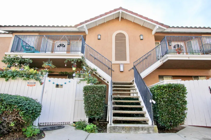 Two-storey townhouses with exterior staircase and orangish paint n the Mission Courts community.