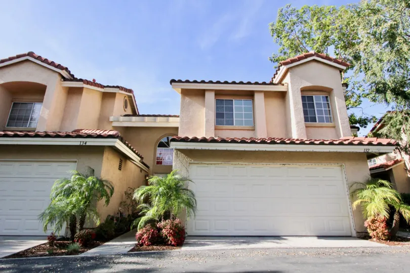 A traditional two-storey townhouses with potted palm plants in the Mission Greens community.
