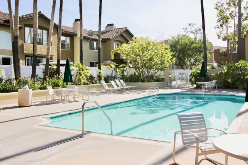A swimming pool area beside a housing comlex with palm trees