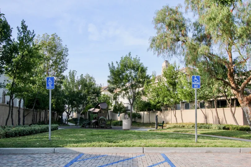 Two handicap parking signs sit in the grass near a brick driveway in Sea Country homes