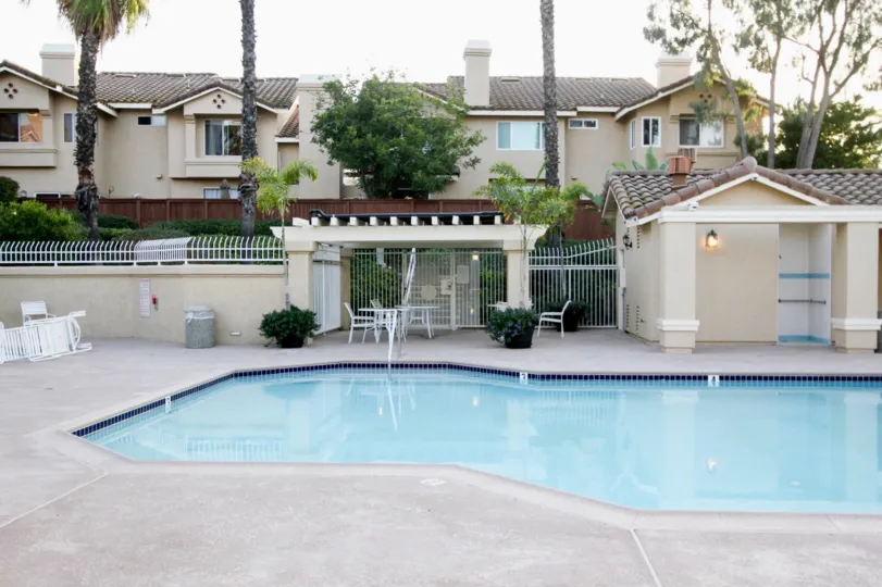 A mostly sunny day by a Sierra Verde pool in an apartment complex with apartments and trees behind the pool