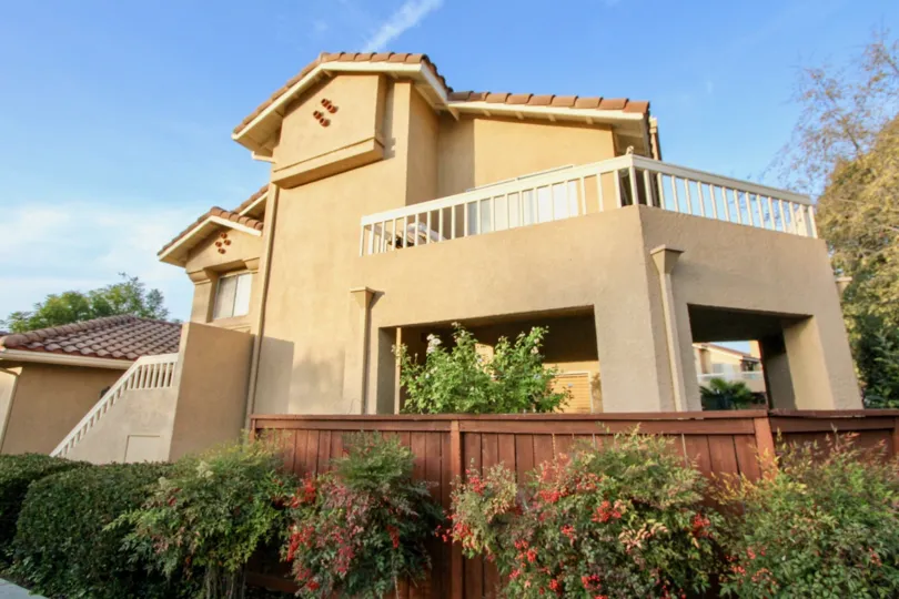 Pretty red flowering bushes sit in front of a privacy fence in Sierra Verde homes