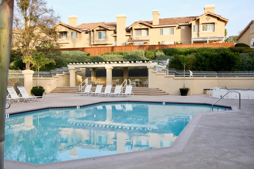 A lovely pool located in the Sierra Verde housing community where there are lounging chairs and a fence surrounding the pool area
