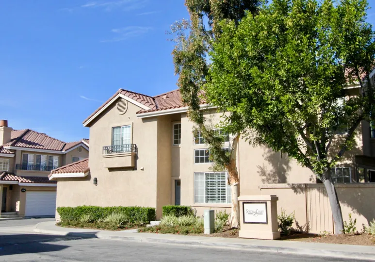 A sunny day by a Sonoma Court multiplex with a Sonoma Court sign in front of it in between two big trees