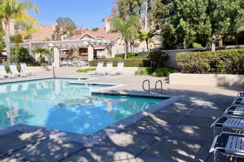 A lovely pool located in the Sonoma Court housing community where there are lounging chairs and a fence surrounding the pool area