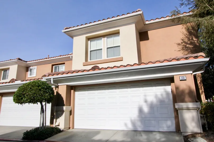 A small well trimmed tree sits in a garden patch in a driveway at the Terracina townhomes