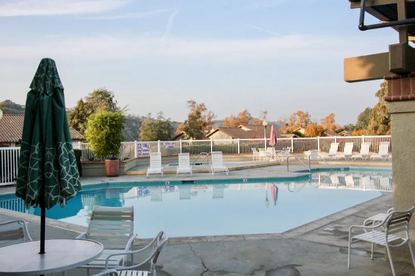 A sunny day in the area of Tierra Linda, outside, pooside, umbrella, chair, fence, trees