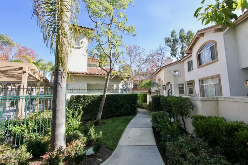 Sunny view of a walkway thru a landscaped two story residential complex.