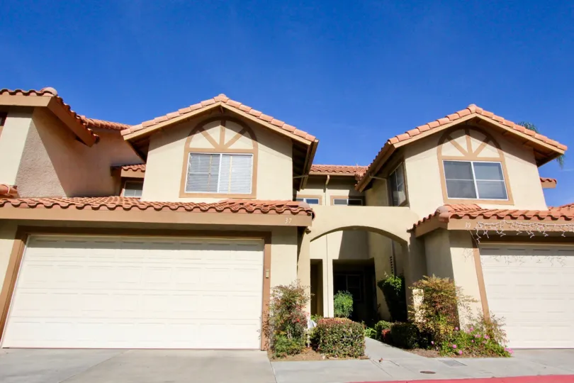 A sunny day at a Vista La Cuesta duplex with matching garages, walkways, and plants by the sides of the garages